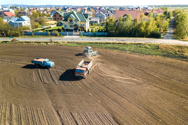 Vista aerea di un trattore che ara il campo dell'azienda agricola di agricoltura nera dopo la raccolta in autunno.