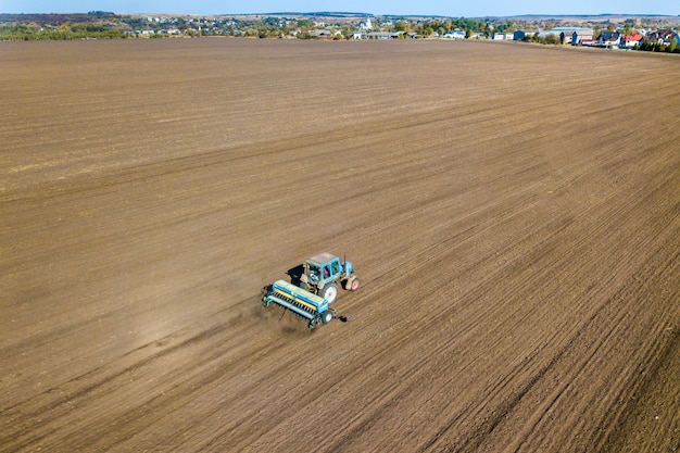 Vista aerea di un trattore che ara il campo nero dell'azienda agricola di agricoltura dopo la raccolta in autunno.