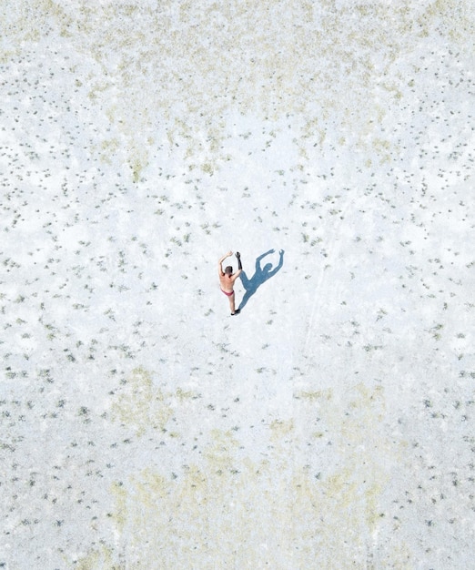 Vista aerea di un uomo senza camicia che cammina su un terreno coperto di neve