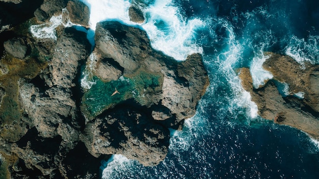 Vista aerea di una donna che nuota nell'acqua in mezzo a una formazione rocciosa in mare