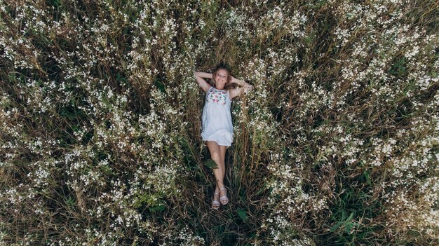 Vista aerea di una ragazza di bellezza che si trova in un giacimento di fiore e nel rilassamento