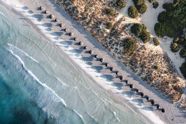 Vista aerea di una spiaggia di sabbia bianca con ombrelloni allineati a Maiorca, in Spagna