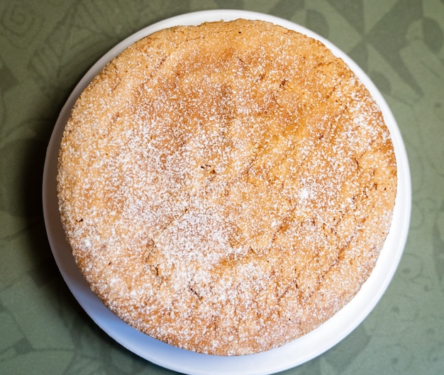 Vista aerea di una torta di santiago rotonda con zucchero cosparso sopra e servita su un piatto bianco