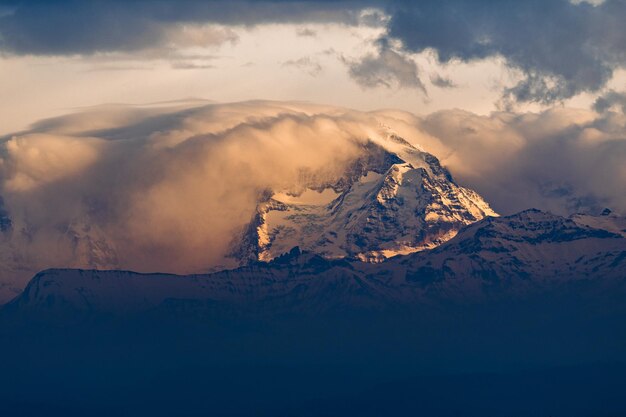 Vista aerea di una vetta di montagna innevata tra le nuvole al tramonto