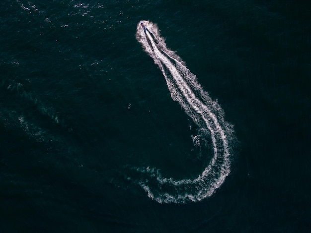 Vista aerea dinamica dello scooter acquatico o della moto d'acqua o del jet da sci che corre attraverso le onde del mare