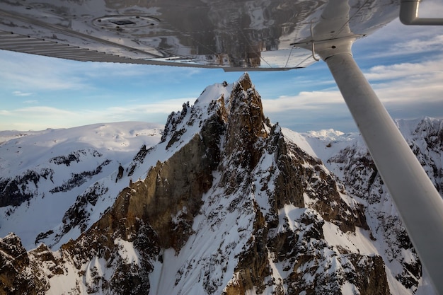 Vista aerea fuori dal finestrino dell'aereo delle montagne rocciose innevate