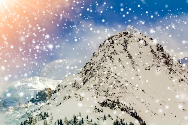 Vista aerea mozzafiato della vetta del Monte Bianco ricoperta di neve brillante, ghiaccio e ghiacciai sotto il cielo blu con nuvole bianche gonfie sul lato francese delle Alpi in una limpida giornata invernale di sole freddo