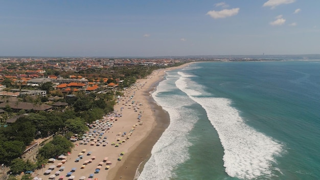 Vista aerea spiaggia di sabbia con persone che si riposano alberghi e turisti ombrelli da sole bali kuta surfisti su