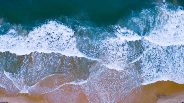 Vista aerea spiaggia sabbiosa e onde Bellissimo mare tropicale al mattino immagine della stagione estiva di Vista aerea drone girato ad angolo alto Onde del mare dall'alto verso il basso