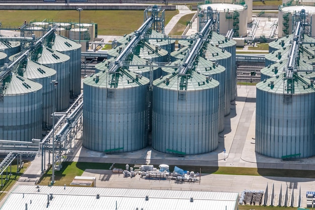 Vista aerea su file di agro silos ascensore per granaio con linea di pulizia dei semi su impianto di produzione di agroprocessing per la lavorazione, asciugatura e stoccaggio di prodotti agricoli