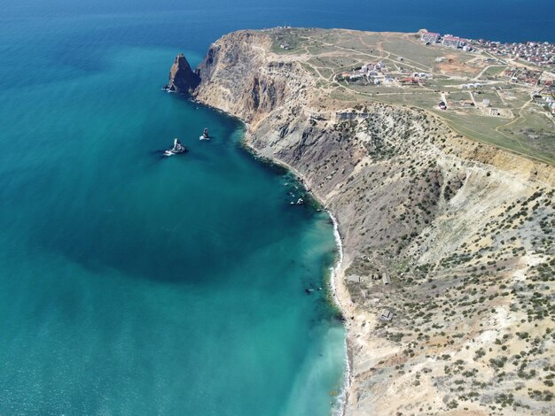 Vista aerea sul mare azzurro calmo e sulle coste rocciose vulcaniche piccole onde sulla superficie dell'acqua in movimento sfocato