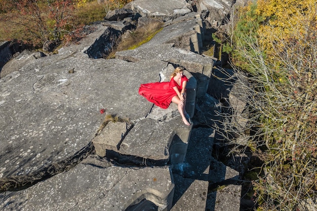 Vista aerea sulla ragazza in abito rosso sdraiato su roccia o struttura in cemento in rovina