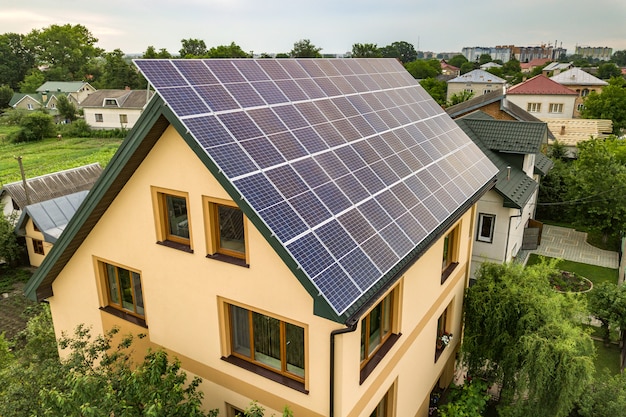 Vista aerea superiore del nuovo moderno cottage casa residenziale con sistema fotovoltaico solare lucido blu pannelli fotovoltaici sul tetto