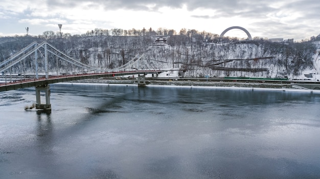 Vista aerea superiore del ponte del parco pedonale in inverno e fiume Dnieper dall'alto, paesaggio urbano di Kiev neve, skyline della città di Kiev, Ucraina