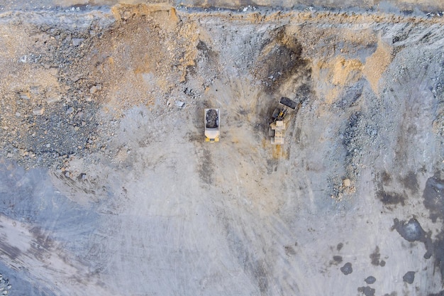 Vista aerea superiore in attrezzature di scavo industriale di grande camion giallo all'interno di una cava di granito a