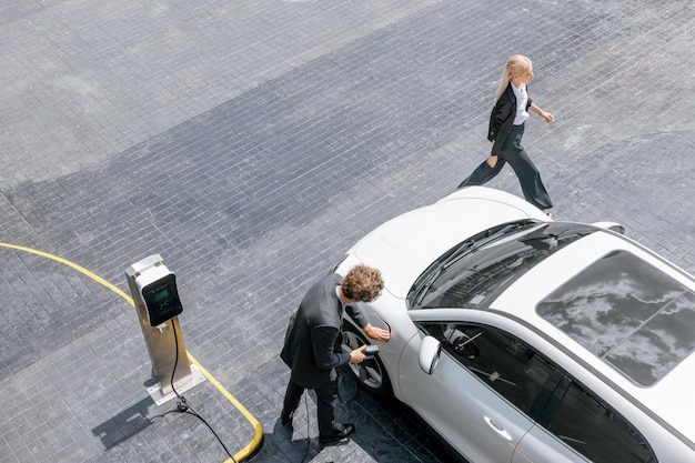 Vista aerea uomini d'affari progressivi con auto EV e stazione di ricarica