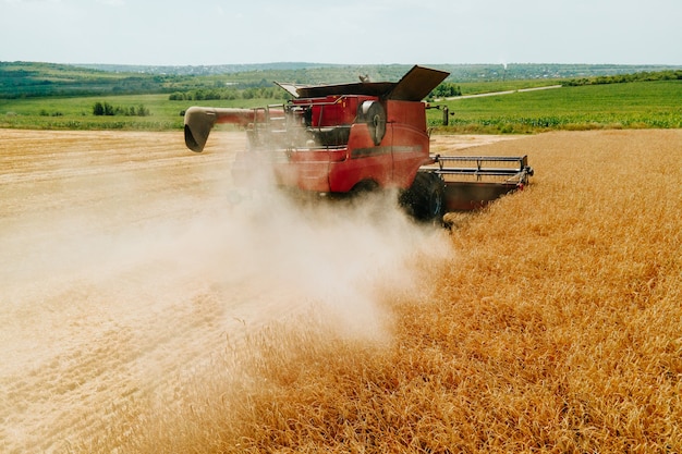 Vista aerea vista frontale della mietitrebbia che raccoglie il grano emette nuvole di polvere e concetto di fumo ...