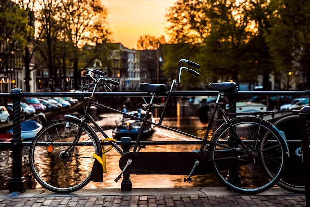 Vista al tramonto con ponte, biciclette e riflesso dell'acqua nella città di Amsterdam, Paesi Bassi