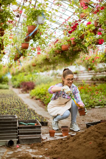 Vista alla giovane donna che lavora nel giardino floreale