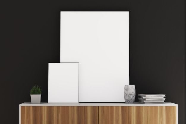 Vista anteriore di due manifesti a cornice verticale di dimensioni diverse in piedi su un comodino di legno in una stanza con pareti nere.