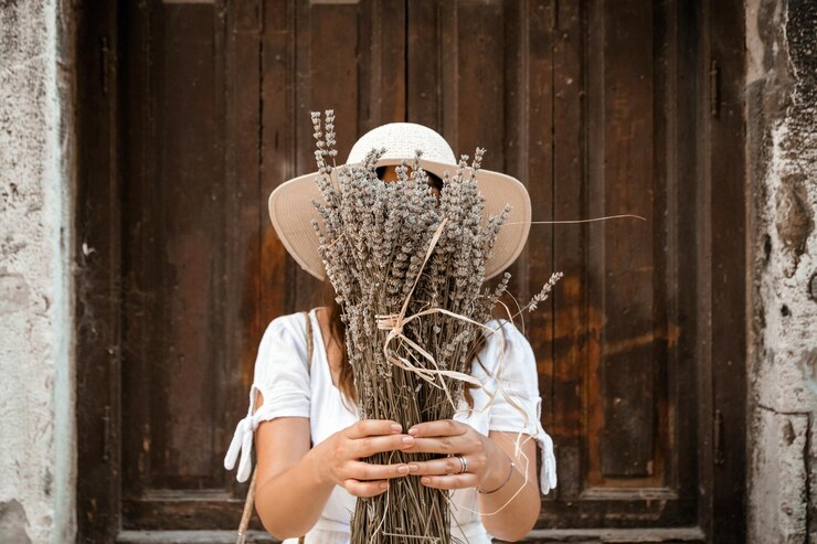 Foto vista anteriore di una giovane donna che tiene un fascio di lavanda secca davanti al viso