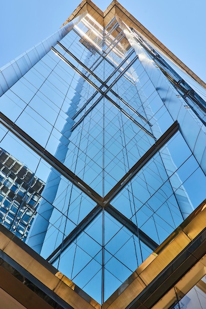 Vista centrale verso l'alto delle finestre blu di un alto grattacielo che crea un'immagine a specchio in un giorno d'estate