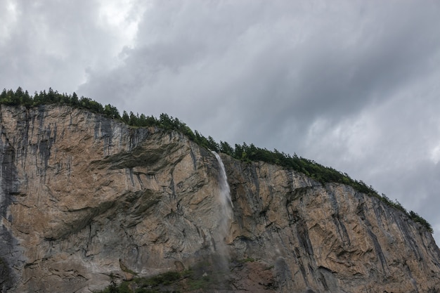 Vista closeup cascata Staubbach caduta in montagna, valle delle cascate nel parco nazionale di Lauterbrunnen, Svizzera, Europa. Paesaggio estivo, tempo soleggiato, cielo azzurro drammatico e giornata di sole
