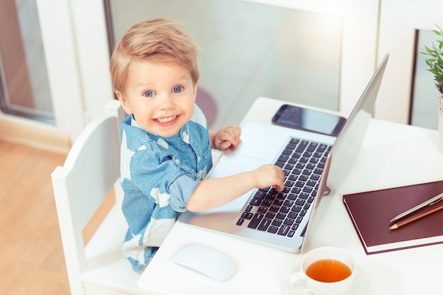 Vista da dietro di 2 anni Bambino che lavora e stampa su computer o laptop