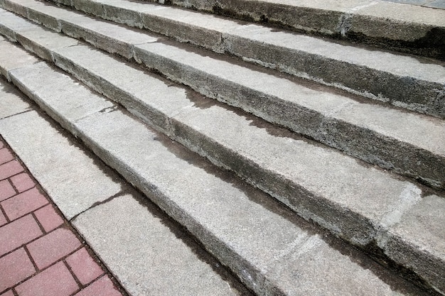 Vista da sopra delle scale concrete grige che conducono alla pavimentazione variopinta all'aperto il giorno soleggiato.