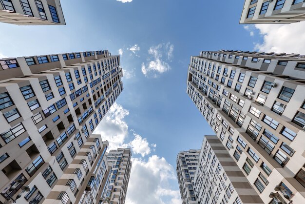 Vista da sotto nel cielo blu con le nuvole di un grande complesso residenziale moderno a grattacielo con arco