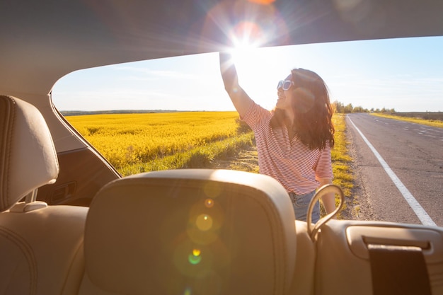 Vista dal bagagliaio di un'auto donna sorridente al concetto di viaggio sul lato della strada