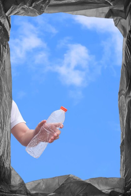 Vista dal basso della mano del giovane che getta una bottiglia d'acqua di plastica nel cestino della spazzatura nel telaio verticale