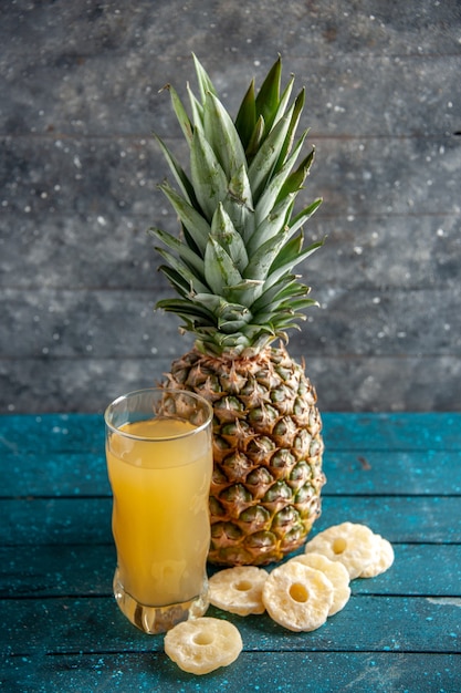 vista dal basso succo di ananas fresco vetro ananas essiccato anelli su sfondo grigio