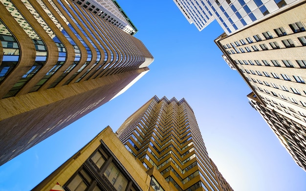 Vista dal basso sulla strada sul quartiere finanziario di Lower Manhattan, New York City, New York, Stati Uniti d'America. Grattacieli alti edifici di vetro negli Stati Uniti d'America. Cielo blu su sfondo. Posto vuoto per spazio di copia.