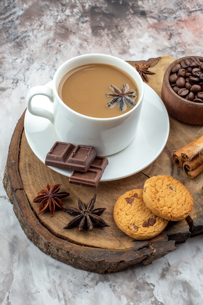 vista dal basso tazza di caffè biscotti chicchi di caffè tostati in ciotola di legno cioccolato bastoncini di cannella legati con corda anice su tavola di legno sul tavolo