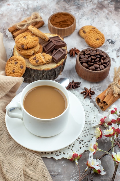 vista dal basso tazza di caffè ciotola con chicchi di caffè tostati cioccolato bastoncini di cannella biscotti sul tavolo