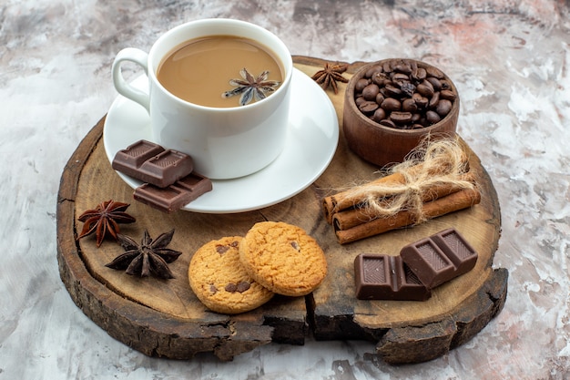 vista dal basso tazza di caffè con biscotti all'anice chicchi di caffè tostati in una ciotola di legno bastoncini di cannella al cioccolato legati con corda anice su tavola di legno sul tavolo