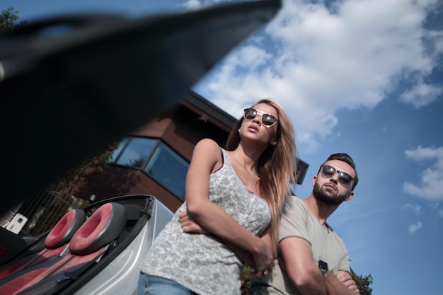 Vista dal bassobella coppia in piedi vicino a un'auto decappottabile