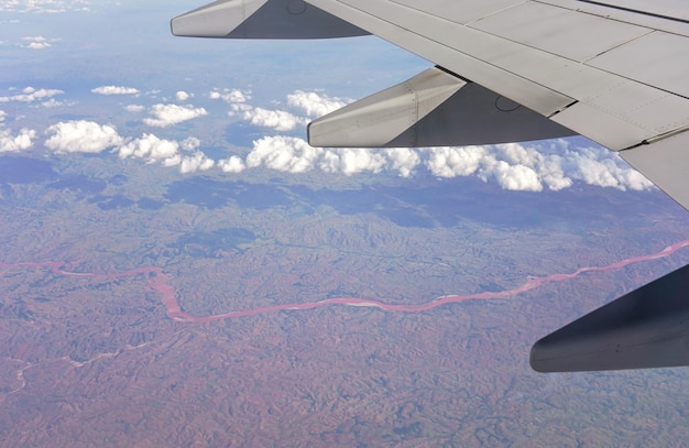 Vista dal finestrino del passeggero dell'aereo commerciale, paesaggio africano montuoso sfocato visibile sotto l'ala dell'aereo