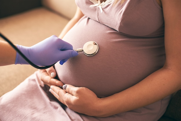 Vista dal lato del medico femminile che esamina la donna incinta