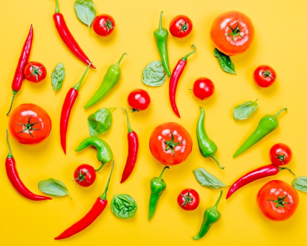 Vista dall'alto a Peperoncino e pomodori con basilico su sfondo giallo