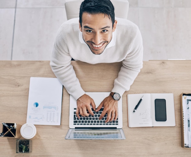 Vista dall'alto al lavoro e uomo d'affari che digita sul laptop facendo ricerche su progetti di business online e scrivendo documenti Lavoro dall'alto e ritratto di lavoratore maschio in ufficio con notebook e telefono