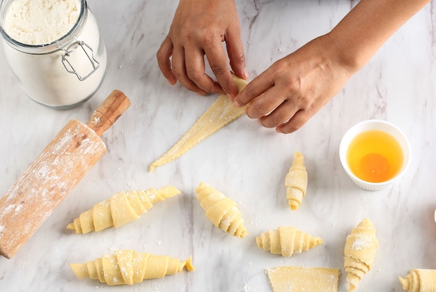 Vista dall'alto arrotolare la pasta a mano femminile in rotoli, processo di cottura che fa croissant. Focus selezionato, Concept for Bakery