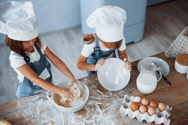 Vista dall'alto. Bambini di famiglia in uniforme bianca da chef che preparano il cibo in cucina.