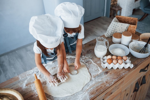 Vista dall'alto. Bambini di famiglia in uniforme bianca da chef che preparano il cibo in cucina.