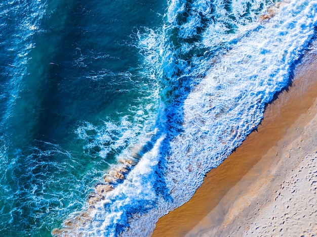 Vista dall'alto bellissima spiaggia con onde che si infrangono sulla spiaggia di sabbiaIncredibile superficie del mare in riva al mare Incredibile bellissima spiaggia di sabbiaNatura e sfondo di viaggio