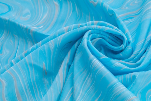 Vista dall'alto blu della seta di colore di base, tessuto con seta motivo marmo blu, ondulato, a spirale, piega, vortice, sfondo, sfondo di stoffa, con spazio per la copia per il testo