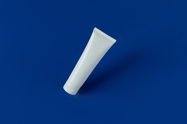 Vista dall'alto bottiglia tubo bianco vuoto con crema lozione o detergente su sfondo blu
