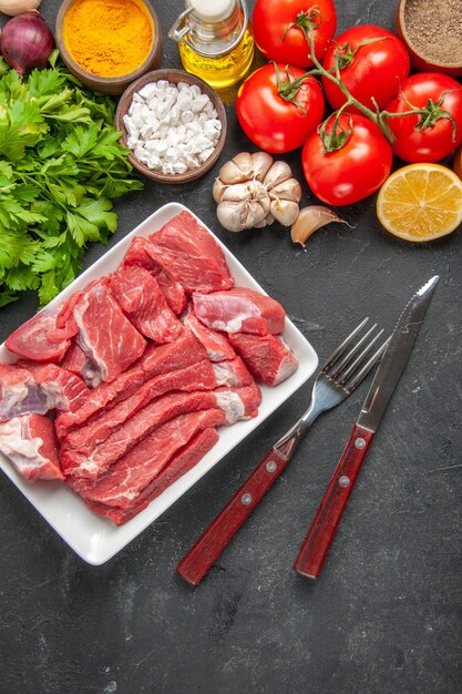 vista dall'alto carne fresca affettata con condimenti verdi e pomodori rossi