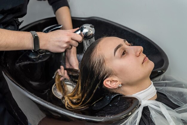 Vista dall'alto come un maestro colorista lava i capelli della testa di una giovane ragazza in un salone di bellezza